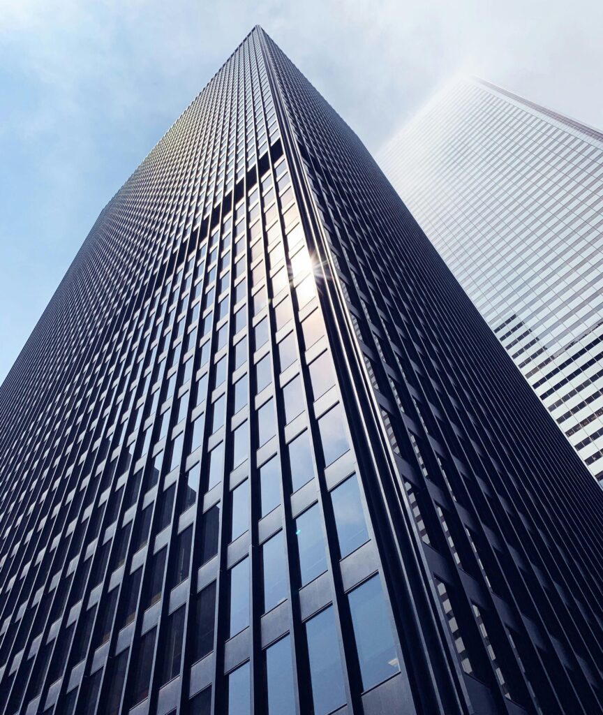 Low angle view of a sleek skyscraper with glass facade in downtown Toronto, capturing sun glare.